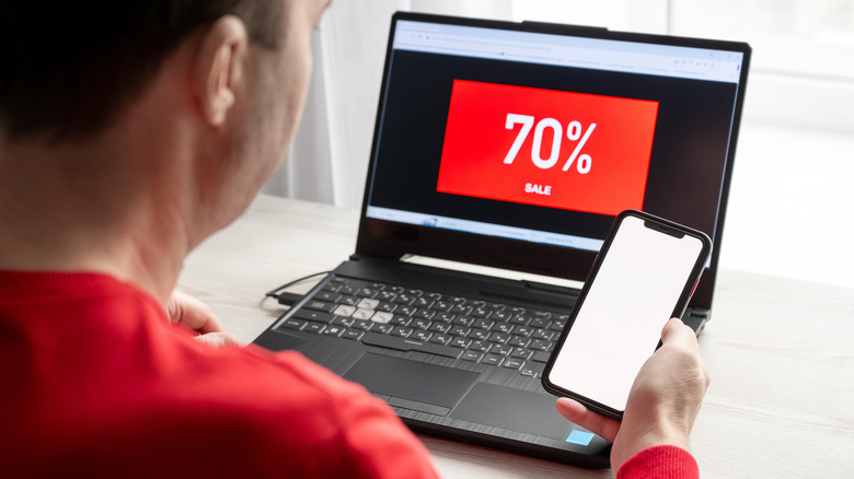 Man looking at computer screen that reads "70% sale"