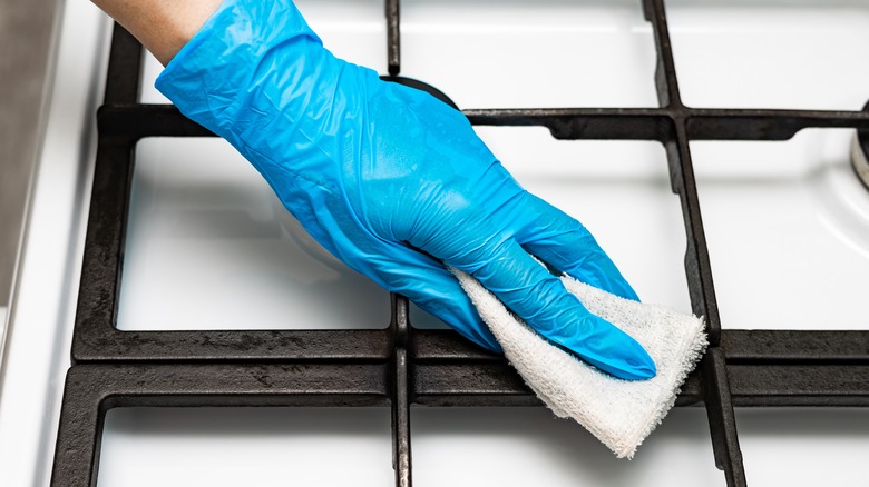 Blue gloved hand cleaning stovetop grates