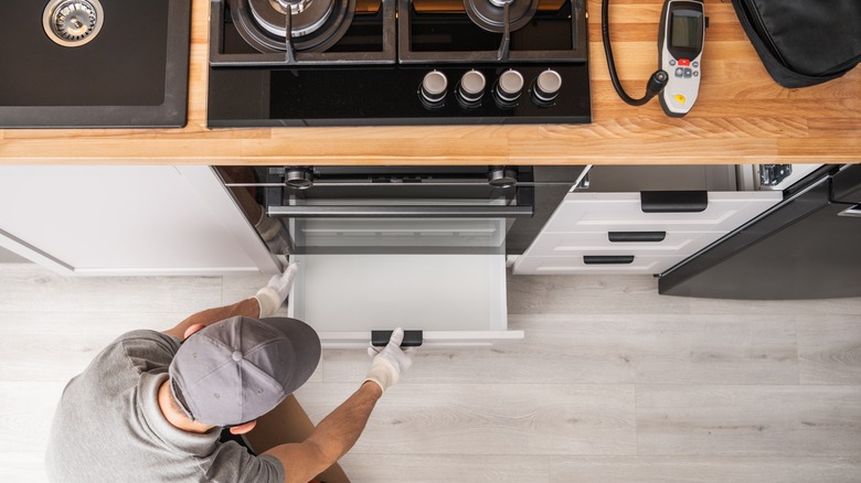 Overhead shot of man pulling out drawer under stove