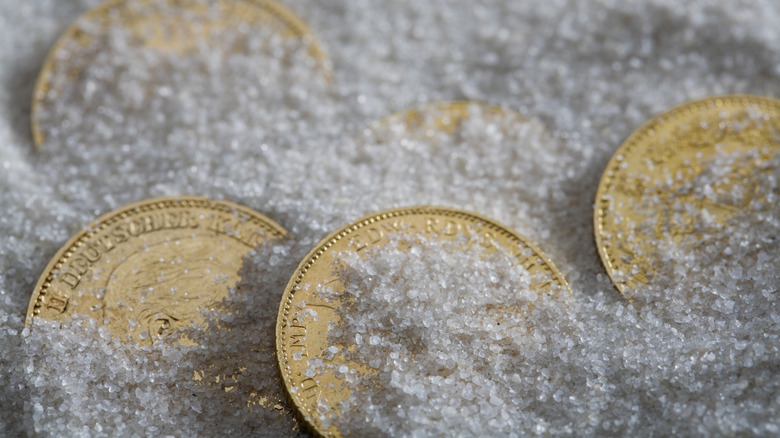 Gold coins partially buried in salt