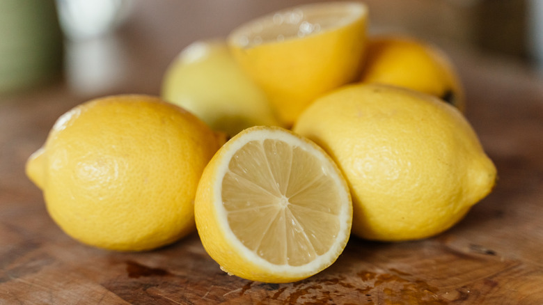 lemons on a wooden background with one lemon sliced in half