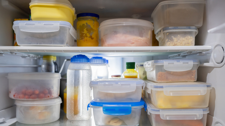 fridge shelves full of plastic storage containers with food inside