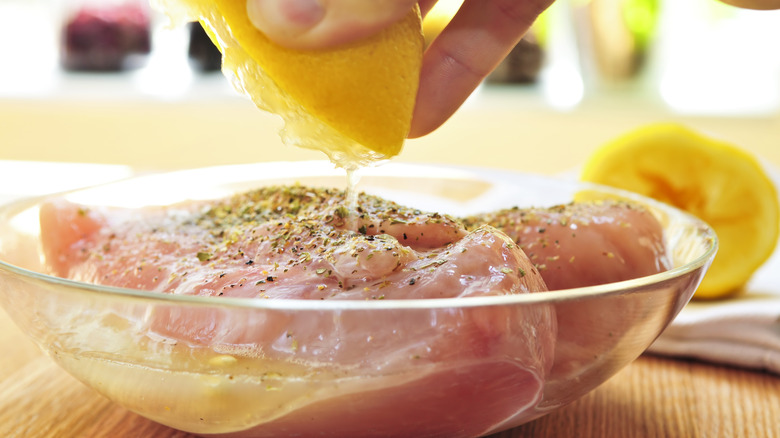 squeezing lemon onto marinating chicken