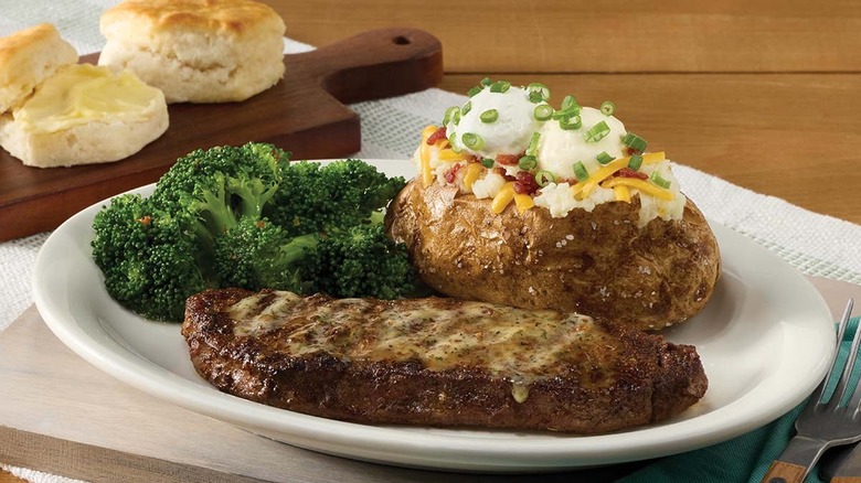 new york strip steak on a plate with broccoli and a loaded baked potato