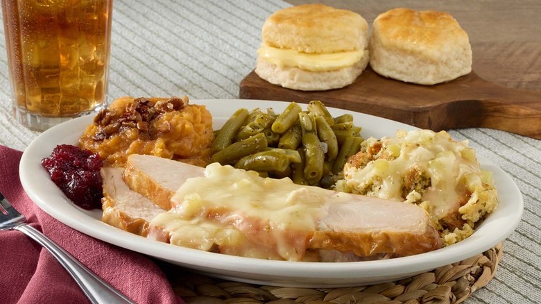 sliced turkey with gravy and sides on a white plate