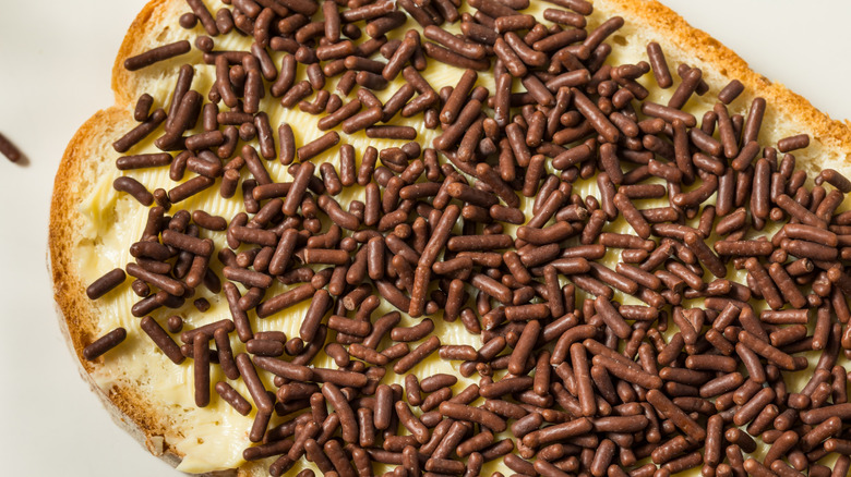 A slice of bread with hagelslag all over it.