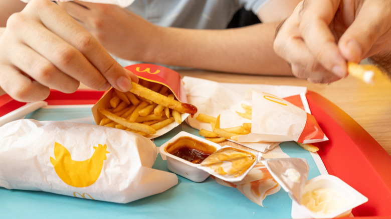 Two people dipping McDonald's fries in sauce