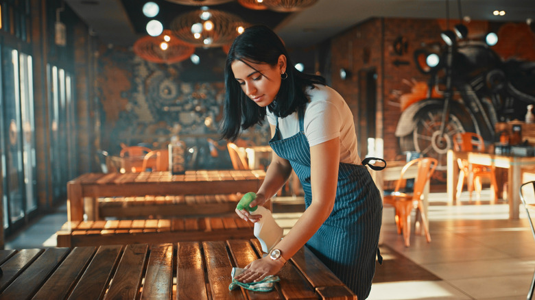 Woman cleaning restaurant table