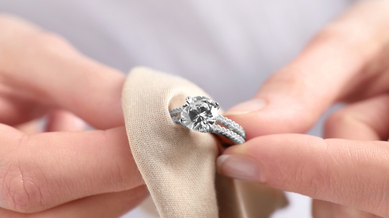 Hands cleaning a diamond ring