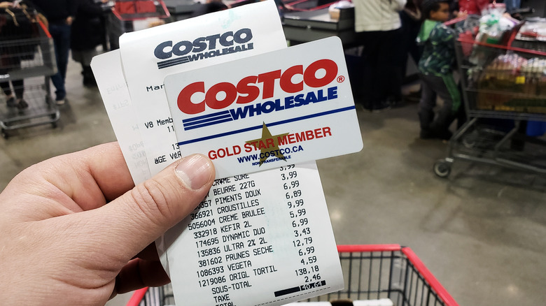 Hand holding a Costco receipt and membership card