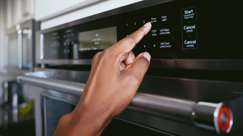 A hand setting the timer on an oven