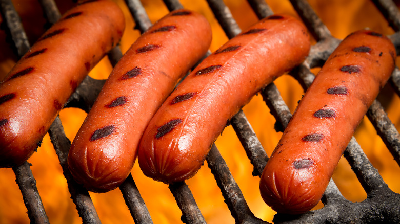 Hot dogs over a grill flame