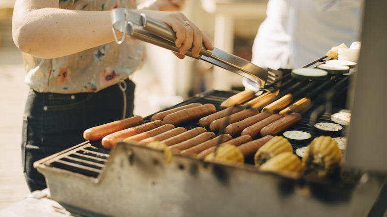 Person cooking grilled hot dogs