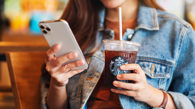 Woman holding phone and Starbucks iced coffee