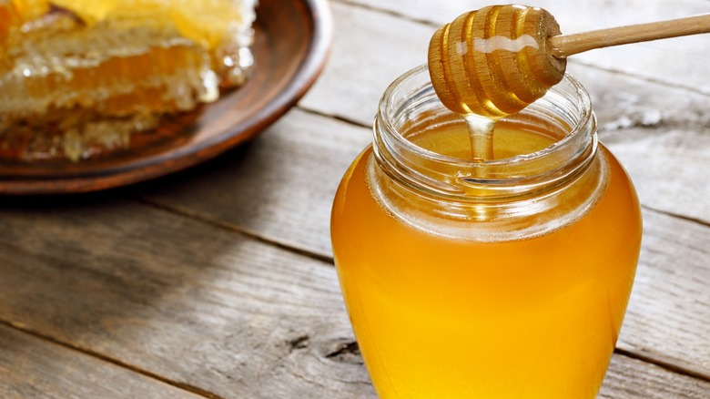 Jar of honey with wooden dipper