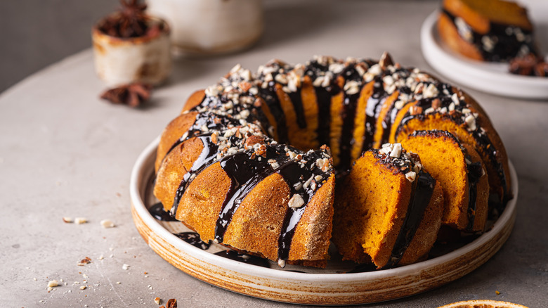 A bundt cake with chocolate glaze and chopped nuts