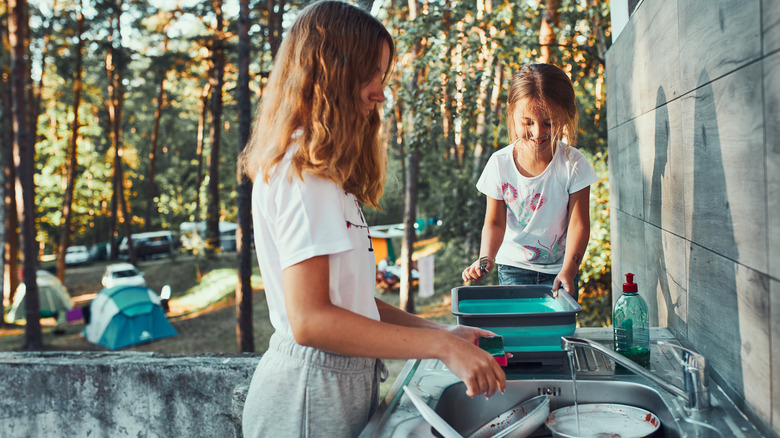 girls washing camping dishes