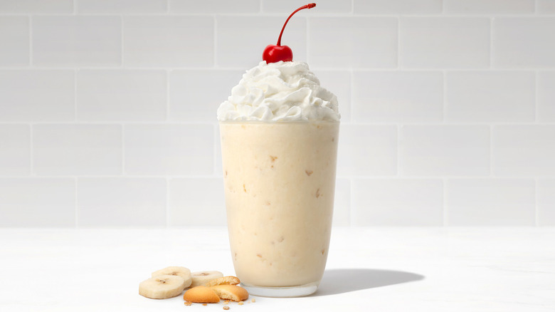 A banana pudding milkshake has whipped cream and a cherry on top.