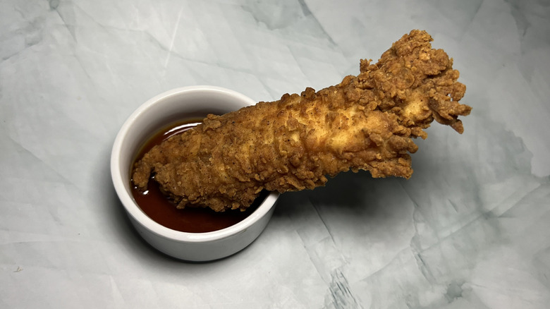 An Original Recipe Tender dipped in sauce.