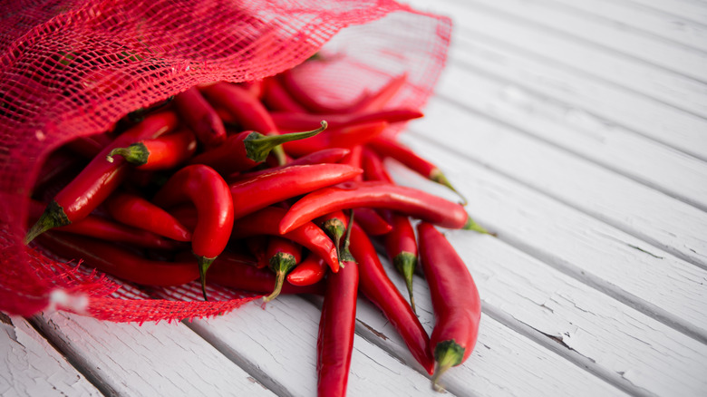 red chili peppers spilling out of a red netted bag