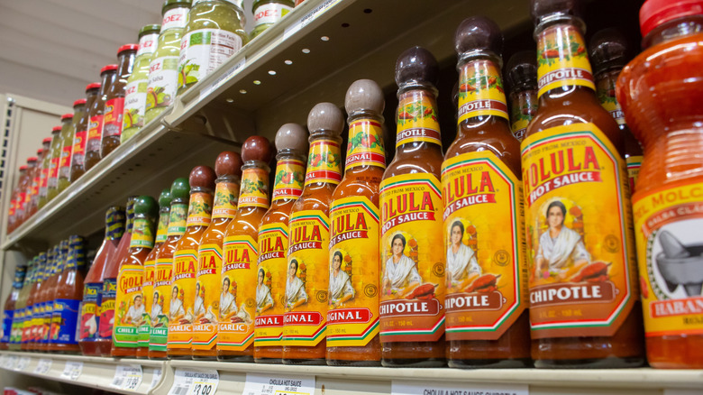 A grocery store shelf of Cholula and other hot sauces