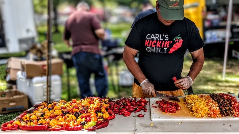 man chopping chili peppers at an event