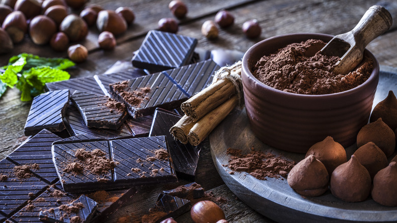 Stacks of dark chocolate squares are arranged with chocolate ingredients like powder.
