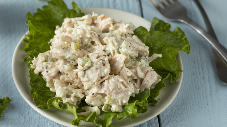 Chicken salad sitting on a lettuce leaf on a plate