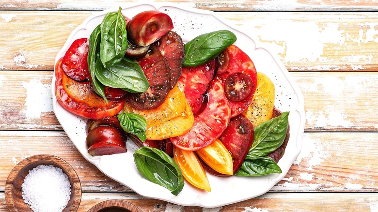 Sliced heirloom tomatoes with salt, pepper, and fresh basil