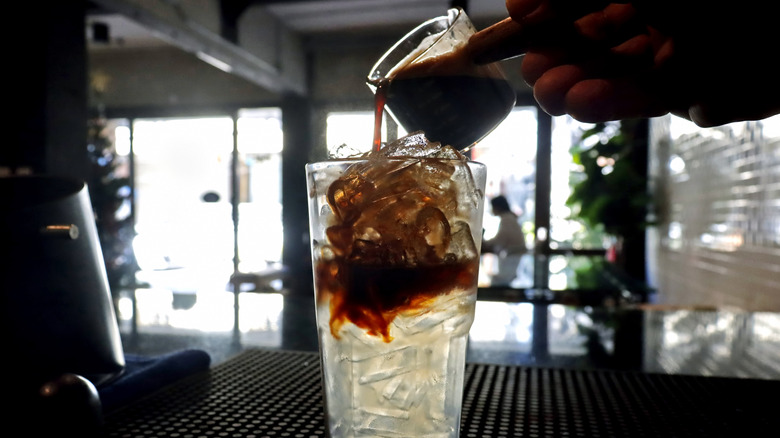 Barista pouring espresso over iced coconut water