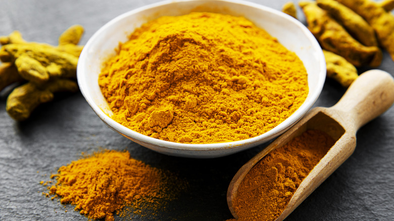 Bowl of yellow curry powder with wooden scoop