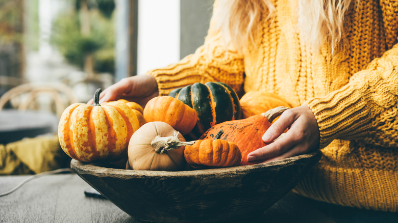 Person holding basket of pumpkins