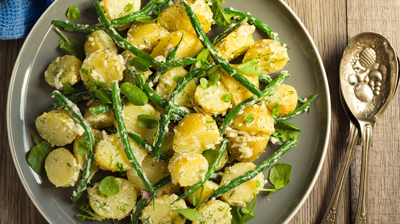 plate of potato salad with green beans and spoons
