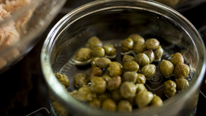 Open glass jar of brined capers