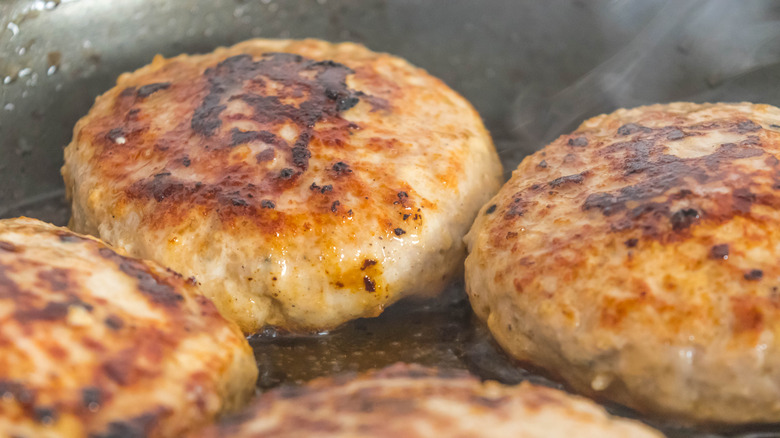 Turkey burgers cooking in pan