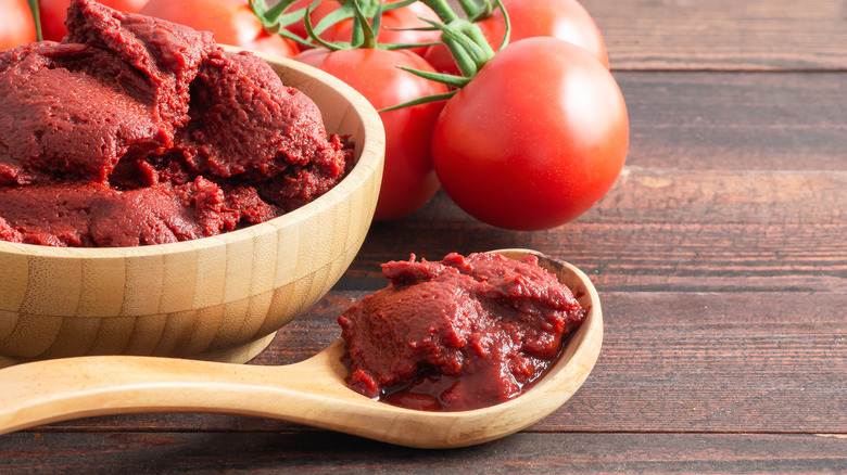 Wooden spoon and bowl of tomato paste.