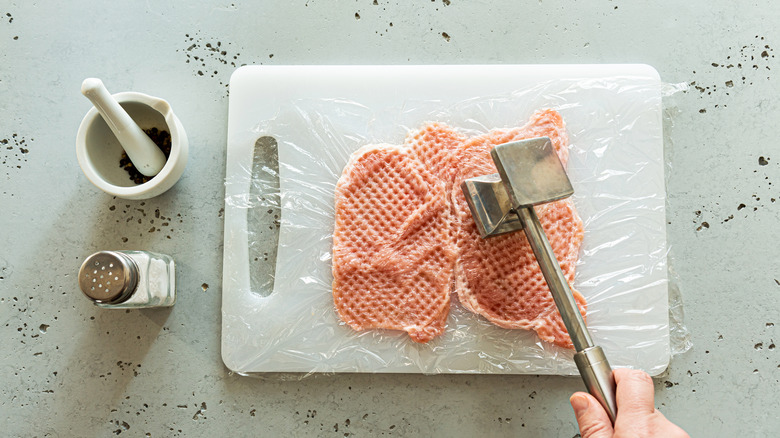 Man tenderizing pork chops