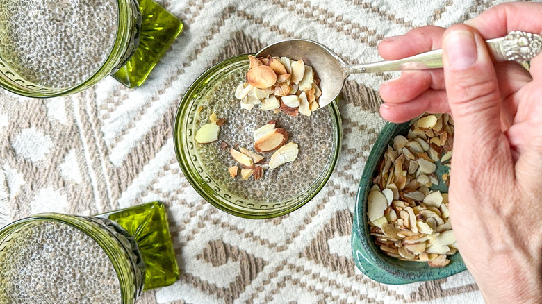 Sprinkling toasted almonds on top of chai chia pudding in serving dishes