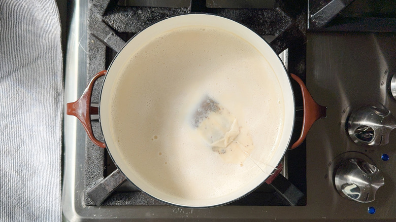 Chai tea bags steeping in almond milk in saucepot on stovetop