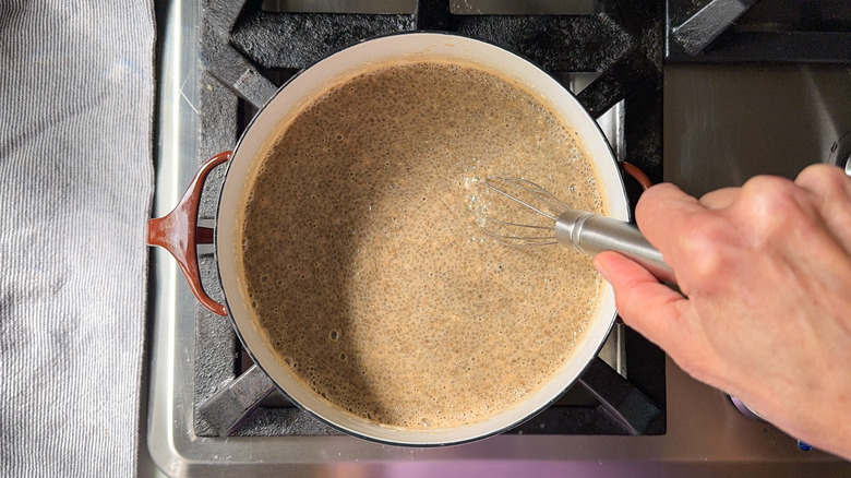 Whisking chai maple syrup into almond chia pudding in saucepot on stovetop