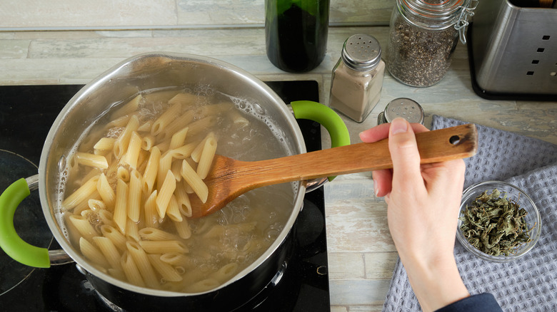 Person stirring a pot full of pasta and water