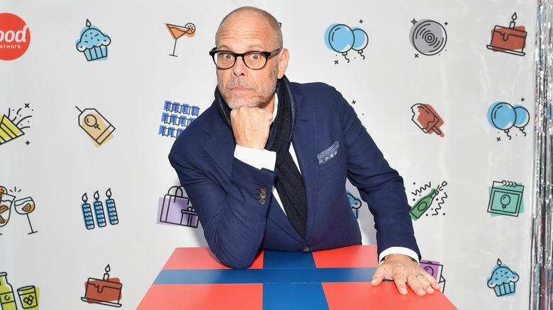 Alton Brown posing with his chin in his hand at an event