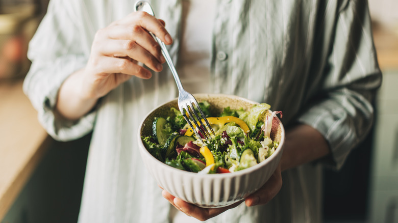 Person holding a salad and fork