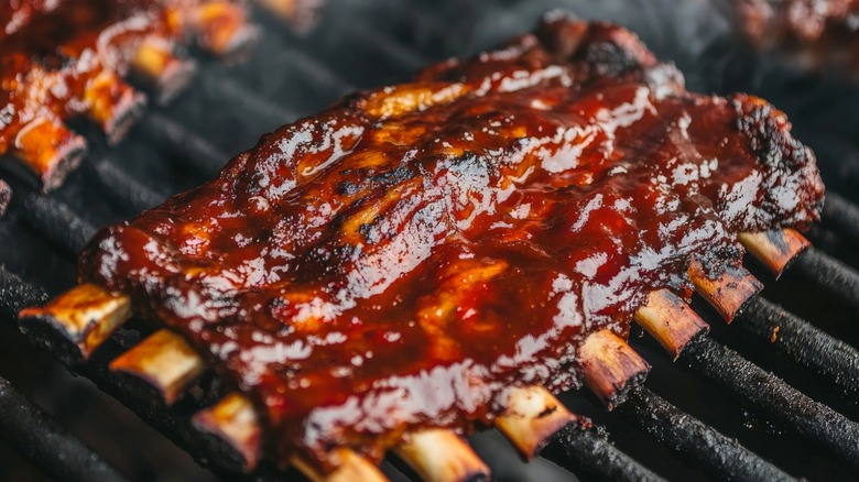 Barbecue ribs covered in sauce on a grill