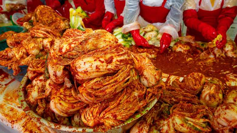 hands mixing a bowl of kimchi