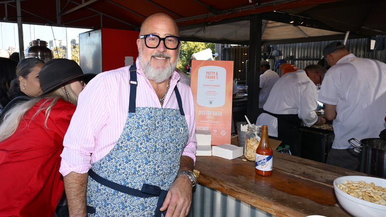 Andrew Zimmern smiling with an apron on