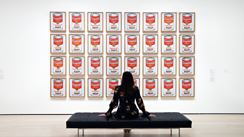 Woman on a bench in front of Andy Warhol's "Campbell's Soup Cans."