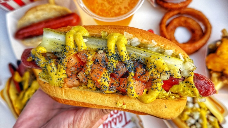 A person holding a Chicago-style hot dog from Tail O' the Pup in Los Angeles