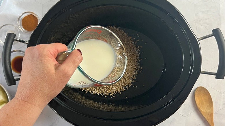 pouring milk into slow cooker oats
