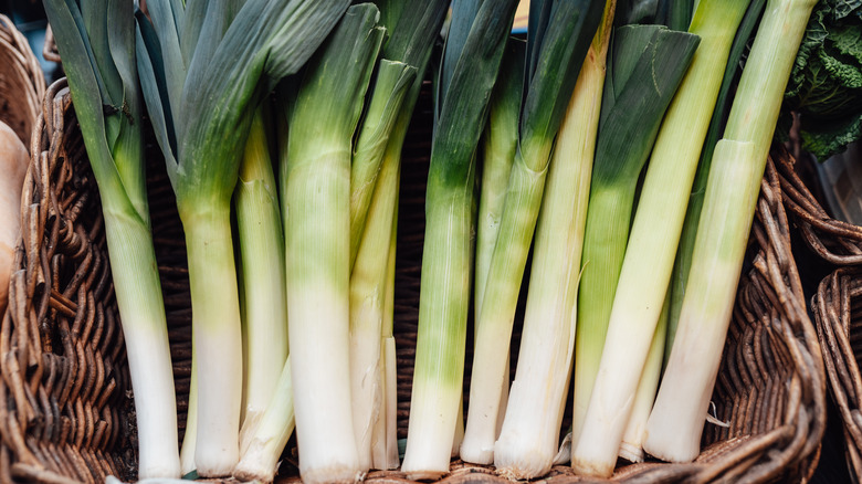 A bundle of fresh leeks in a wooden basket